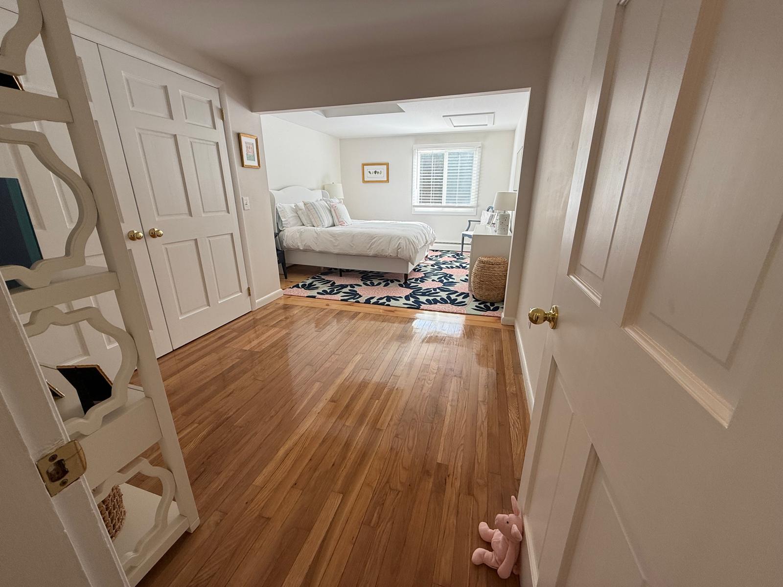 Hardwood hallway leading to a freshly cleaned bedroom
