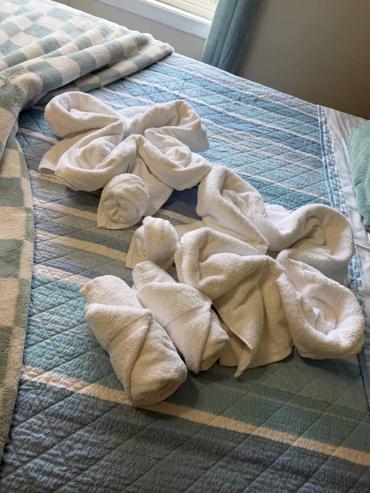 Fresh towels folded on a made bed after a turnover cleaning