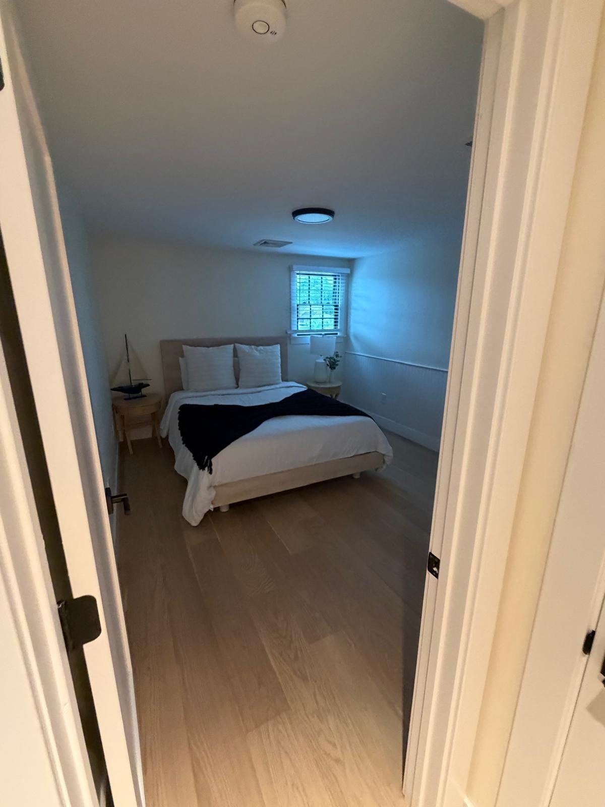 Bright bedroom with made bed and cleaned floors